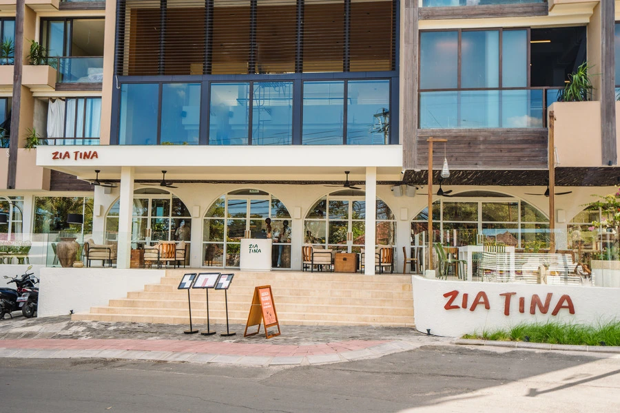 Exterior view of Zia Tina Restaurant with a large glass facade and outdoor seating areas