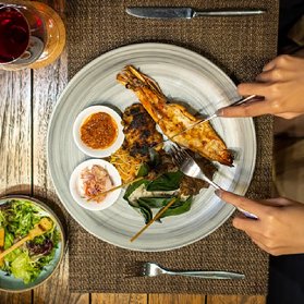 Top-down view of person eating grilled seafood platter